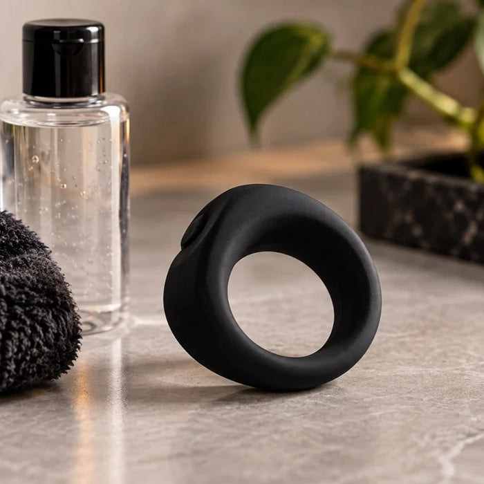 Black silicone cock ring with lubricant and towel on a bathroom vanity