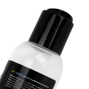 Close-up view of the BUTTR White Cum Lubricant bottle with black cap