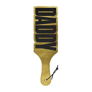 A gold-colored paddle with the word 'DADDY' in bold, capital letters on a shiny surface. The paddle has a handle with a snap button for easy use.